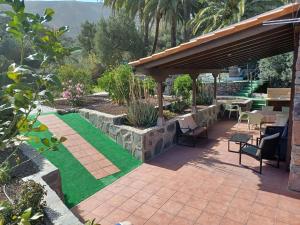 a patio with a table and chairs and grass at Las Palmeras Temisas in Temisas