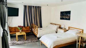 um quarto de hotel com duas camas e um sofá em Private Rooftop Terrace! Luxury London Penthouse, Unforgettable Views, Prime Location em Londres