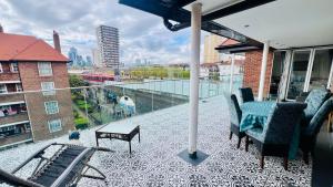 uma varanda com cadeiras e uma mesa num edifício em Luxury Private Rooftop Terrace! Contemporary Penthouse with Amazing City Views in Zone-1 em Londres