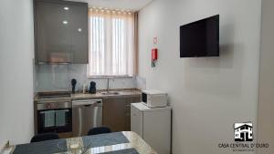 a kitchen with a table and a tv on a wall at Casa Central D'ouro in Tabuaço +5 photos