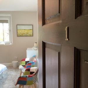 Cette chambre dispose d'une porte avec des chaises et un lit. dans l'établissement Belford House Self Check-in Rooms, à Haltwhistle