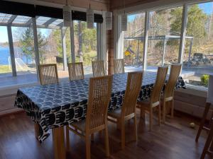 a dining room with a table and chairs and windows at Villa Mustalahti in Mikkeli