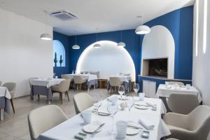 restauracja z białymi stołami i krzesłami oraz niebieskimi ścianami w obiekcie Hotel Approdo di Venere w mieście Vieste