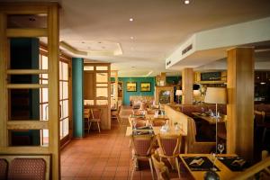 uma sala de jantar com mesas e cadeiras num restaurante em Strandhotel Seehof em Langlau