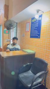 un hombre sentado en un mostrador con una silla en Hotel Image Residential Near Square Hospital, en Dhaka