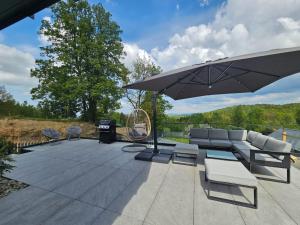 a patio with a couch and an umbrella and a grill at Dom w Czerwonej Dolinie Haus im Roten Tal Seidorf Sosnówka` in Sosnówka
