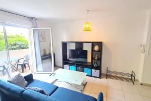 a living room with a blue couch and a tv at Charming 45m in Sarrola carcopino in Sarrola-Carcopino