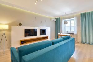 グディニャにあるCITYSTAY Pilsudskiego Apartmentのリビングルーム(青いソファ、テレビ付)