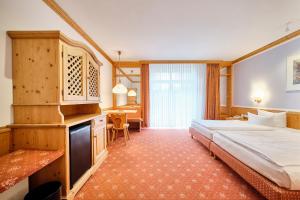 ein Hotelzimmer mit einem großen Bett und einem Schreibtisch in der Unterkunft Strandhotel Seehof in Langlau