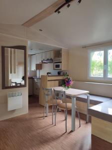 a kitchen and dining room with a table and chairs at Mobil home Gîte Canal Nantes à Brest 40 minutes Nantes et Saint-Nazaire in Guenrouet