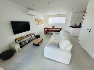 a living room with a white couch and a flat screen tv at Villa Domaine U Murtonu in Porto-Vecchio