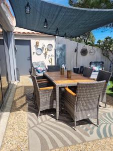 einen Holztisch und Stühle auf einer Terrasse in der Unterkunft Torreilles plage: villa atypique bord de mer méditerranée in Torreilles