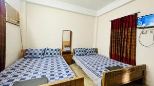 Habitación con 2 camas y espejo. en Hotel Image Residential Near Square Hospital, en Dhaka