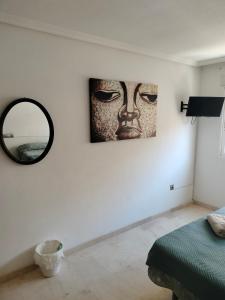 un dormitorio con una pintura de una cara en la pared en HOLIDAY CENTRE DELUXE, en Alicante