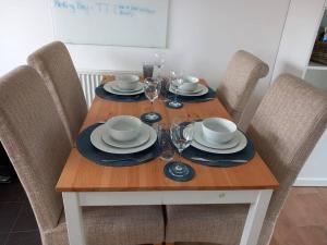 - une table en bois avec des assiettes et des verres à vin dans l'établissement NEW 2 Bedroom Flat in Hatfield, à Hatfield