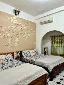 - une chambre avec 2 lits et un mur orné de fleurs dans l'établissement Đức Long, à Vung Tau