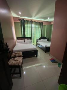 a bedroom with two beds and a couch and a window at Suzie hotel in Kampala