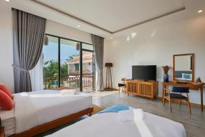 a hotel room with two beds and a flat screen tv at Én Mansion Hoi An in Hiếu Nhơn
