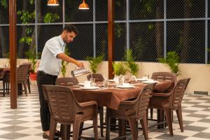 a man standing at a table in a restaurant at Pristine Woods Resort in Dehradun