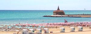 a beach with a large group of umbrellas and the ocean at Elegante affascinante Appartamento in centro storico in Caorle