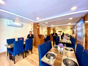 薩姆沙巴德的住宿－Hotel Sky International- Airport Zone Hyderabad，两人在带桌子和蓝色椅子的餐厅