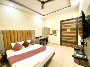 Hotel Sky International- Airport Zone Hyderabad في شامشاباد: غرفة نوم بسرير ومكتب وتلفزيون