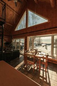 a dining room with a table and some windows at Le Petit Domaine Caché - Lac-Simon in Lac-Simon