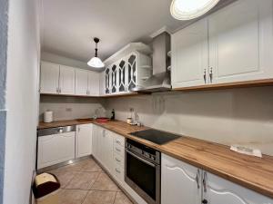 Una cocina con gabinetes blancos y encimera. en Serenity, en Gjirokastra