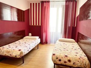 2 camas en una habitación con paredes rojas en Hostal Abaaly, en Madrid