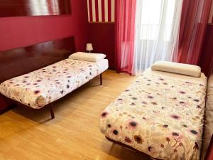 two beds in a room with red walls at Hostal Abaaly in Madrid