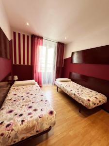 2 camas en una habitación con rayas rojas y blancas en Hostal Abaaly, en Madrid