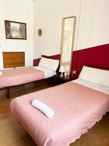 Habitación de hotel con 2 camas y espejo en Hostal Abaaly, en Madrid