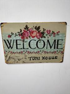 a welcome sign on a wall with flowers at Turi house in Messina