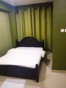 a bed with white sheets in a room with curtains at Suzie hotel in Kampala