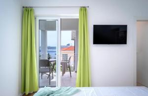a bedroom with green curtains and a room with a table at Blue Lagoon house in Hvar