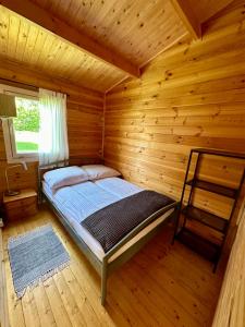 a bedroom with a bed in a log cabin at Projekt Stajnia - Nadmorski Ośrodek Jazdy Konnej - noclegi in Łazy