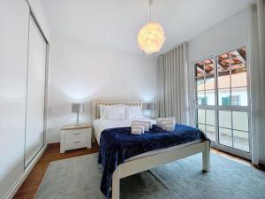 Habitación blanca con cama y lámpara de araña. en Moradia Uriel en Santa Cruz