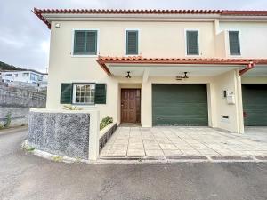 uma casa branca com uma garagem e uma entrada em Moradia Uriel em Santa Cruz - Madeira