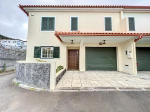 a white house with a garage and a driveway at Moradia Uriel in Santa Cruz