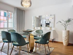 a dining room with a glass table and green chairs at Moradia Uriel in Santa Cruz