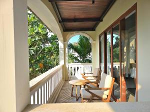 un porche con sillas y una mesa en el balcón en En Retreat Villa Hoi An en Hiếu Nhơn