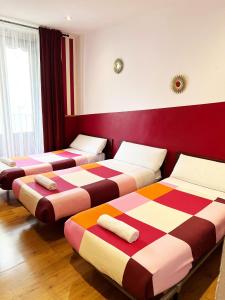 3 camas en una habitación con rojo y blanco en Hostal La Casa de La Plaza, en Madrid