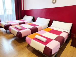 3 camas en una habitación con paredes rojas en Hostal La Casa de La Plaza, en Madrid