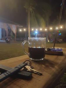 a cup of coffee sitting on a table with keys at JN Cottage dan Camping Ground in Karimunjawa