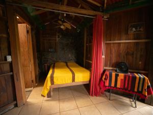 1 dormitorio con 1 cama con cortina roja en 1 bedroom cabin, 3 blocks from beach and center of San Juan, en San Juan del Sur