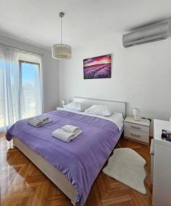 una camera da letto con un grande letto viola con asciugamani di Apartment GIDAS a Zara (Zadar)