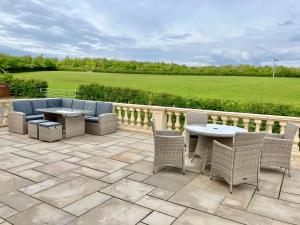 a patio with wicker furniture and a table and chairs at Marehay Hall Farm in Belper