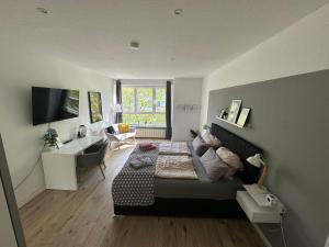 ein Schlafzimmer mit einem Bett, einem Schreibtisch und einem Fernseher in der Unterkunft SunshineLiving Maschsee in Hannover