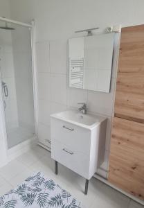 een witte badkamer met een wastafel en een spiegel bij Le Balcon d'Anatole in Le Mans