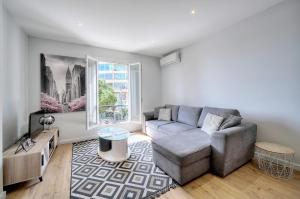 Una sala de estar con un sofá y una ventana. en Le Érvé-350M Plage-Wifi Clim-VCA, en Cannes
